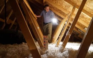 Home inspector inspecting insulation in attic.