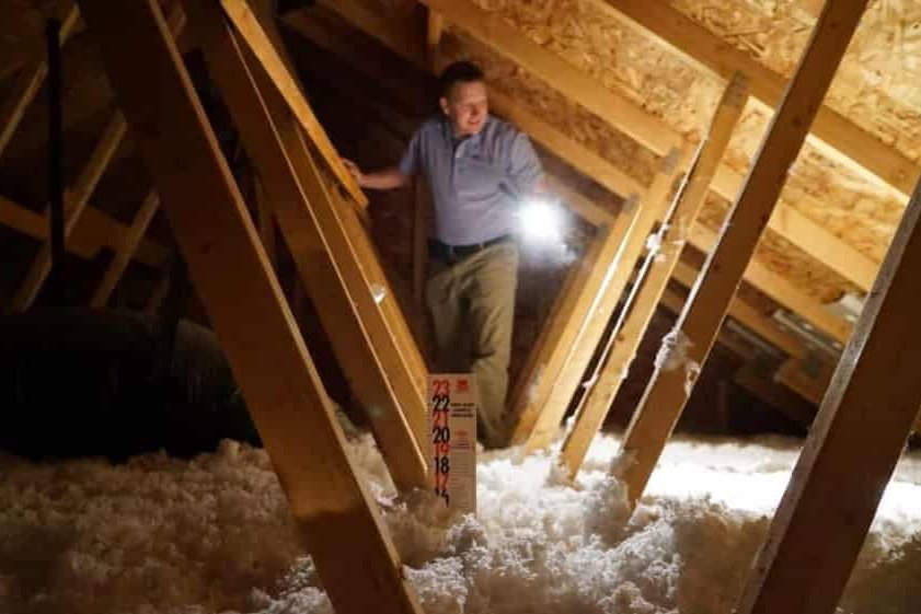 Home inspector inspecting insulation in attic.