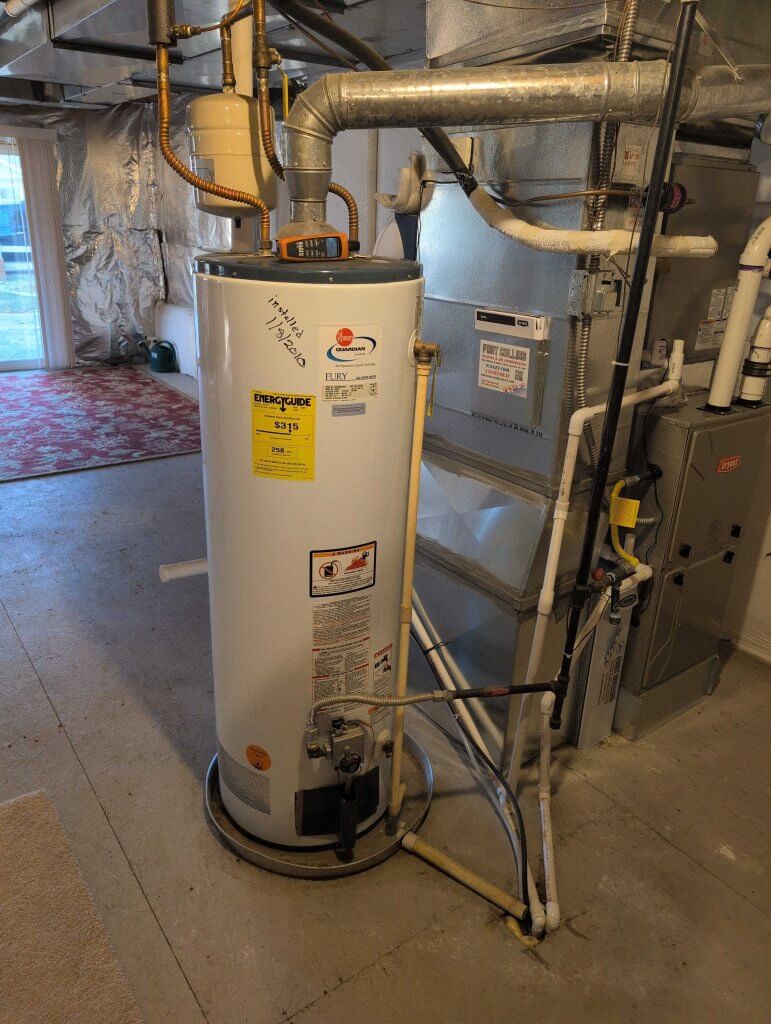 Standard tank water heater installed in a home utility room, showing a large insulated cylinder used for storing hot water.