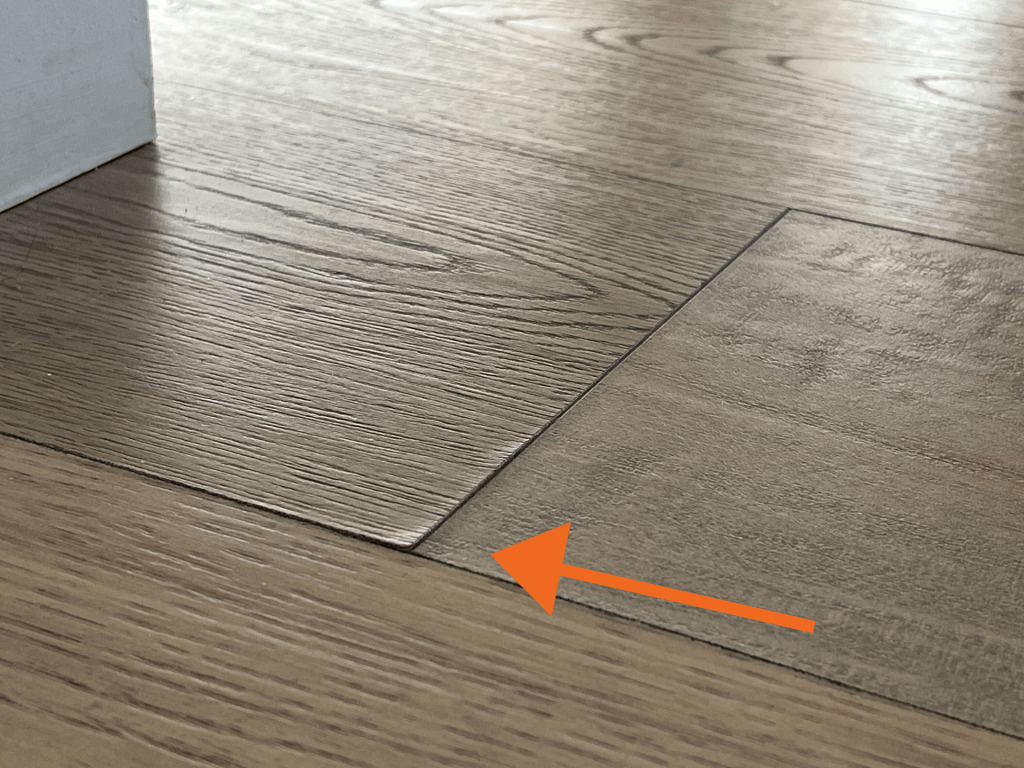 Close-up of separated hardwood floorboards that can cause squeaky floors due to wood movement and gaps between boards.