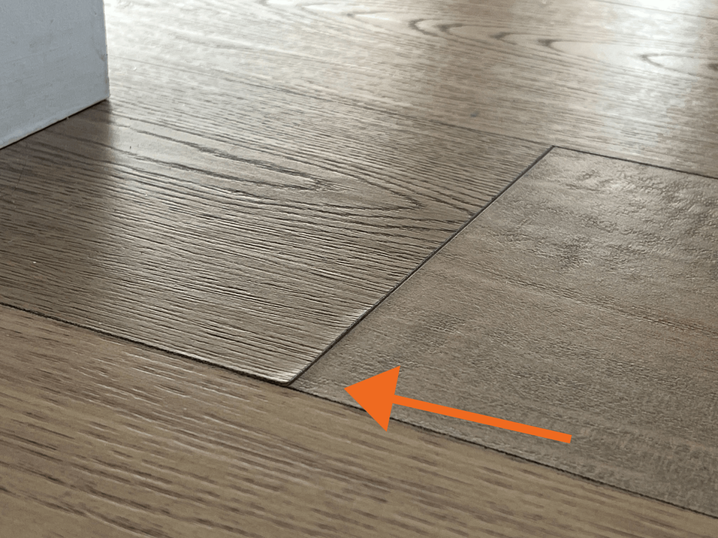 Close-up of separated hardwood floorboards that can cause squeaky floors due to wood movement and gaps between boards.